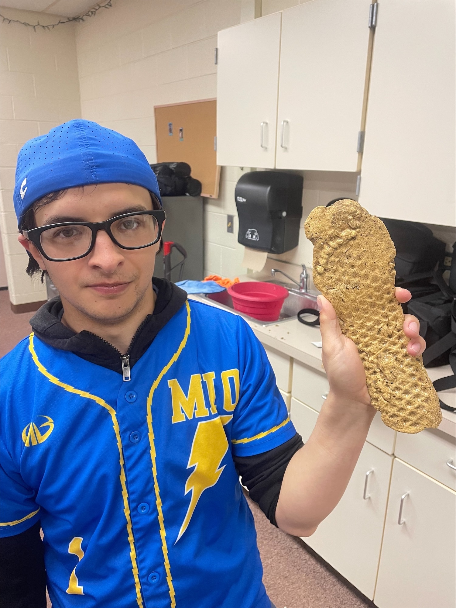 student posing with his cast of his footprint