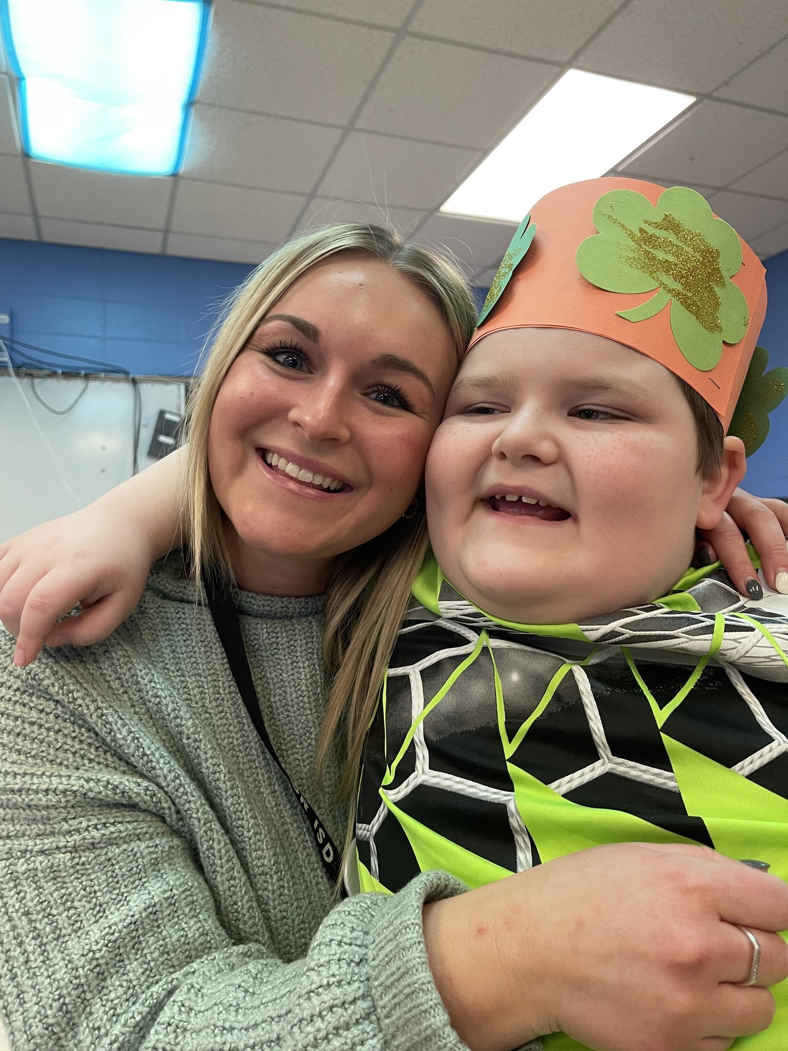 student and teacher hugging and smiling at camera